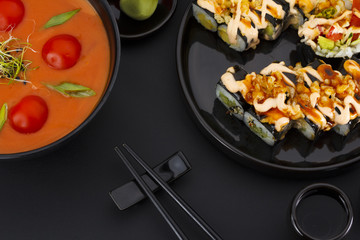 Japanese cuisine. Vegetarian soup with tomato and coconut and crunch sushi roll over black background