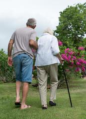 Man helping elderly lady with walking cane