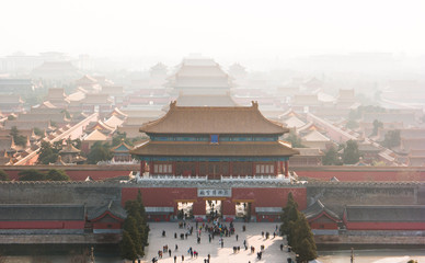 An aerial bird view of the the famous Forbidden City in Beijing, China. The vast area of the architectural complex is covered with evening mist.