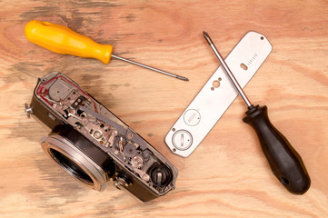Flat lay - broken old vintage film camera and tools (screwdriver) for its repair