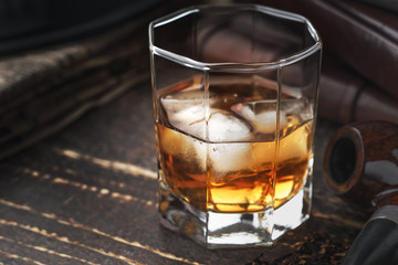 Whiskey with ice and pipe on the wooden table