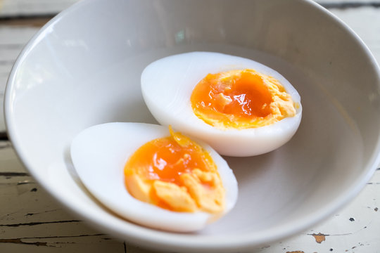 Boiled duck eggs cut in half in white cup on wood table