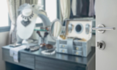 opened white door to blurred wooden dressing table with accessories at home