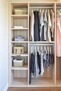 modern closet with row of cloths hanging in wooden wardrobe