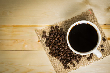 Coffee cup and roasted coffee beans on a wooden table.