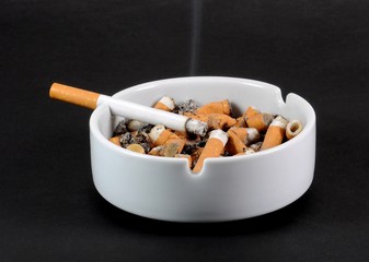 White ceramic ashtray full of smokes cigarettes