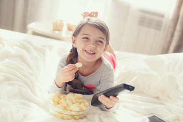 Little girl eating popcorn in bed