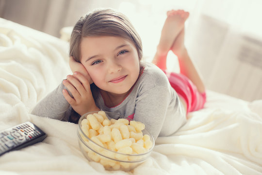 Little girl eating popcorn in bed