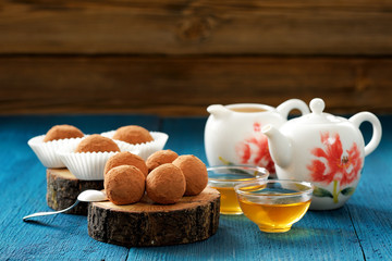 Lentil sweets in cocoa powder on oak board with tea and teapot c