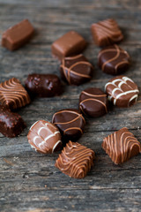 Different types of chocolate candies on a wooden background
