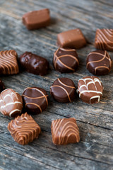 Different types of chocolate candies on a wooden background