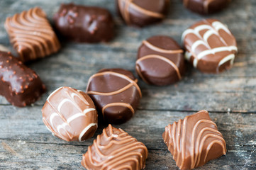 Different types of chocolate candies on a wooden background