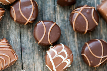 Different types of chocolate candies on a wooden background