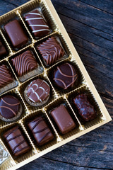Different types of chocolate candies on a wooden background
