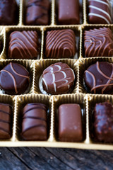 Different types of chocolate candies on a wooden background