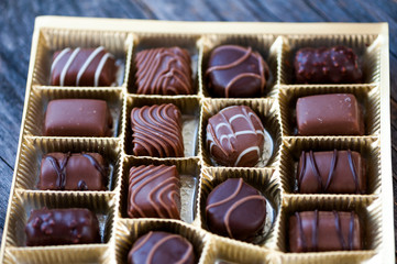 Different types of chocolate candies on a wooden background