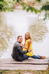 Young man and woman on the nature near lake and forest. Playful couple in love