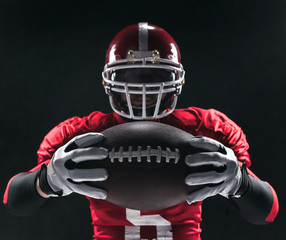 American football player posing with ball on black background © master1305