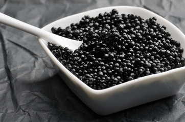 spoon in black caviar close-up in a white bowl horizontal on a d
