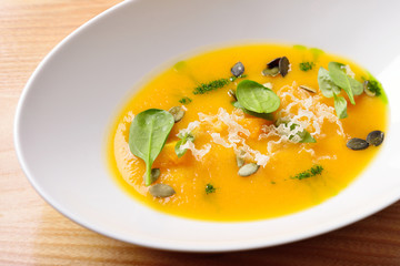 pumpkin cream soup with cheese, greens and pumpkin seeds, isolat