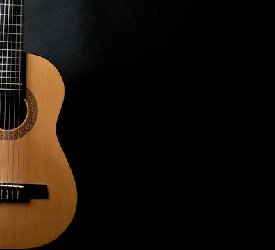 Half of a bright yellow acoustic guitar on a black background (with copy space for your text)
