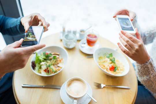 close up of couple picturing food by smartphone