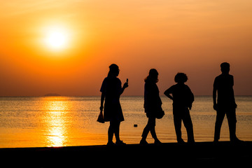 Fototapeta na wymiar the tourist walk at the beach and sunset silhouette at the beach