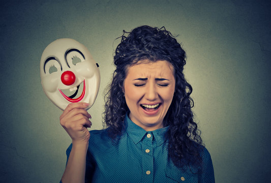 upset crying screaming woman holding a clown mask expressing cheerfulness