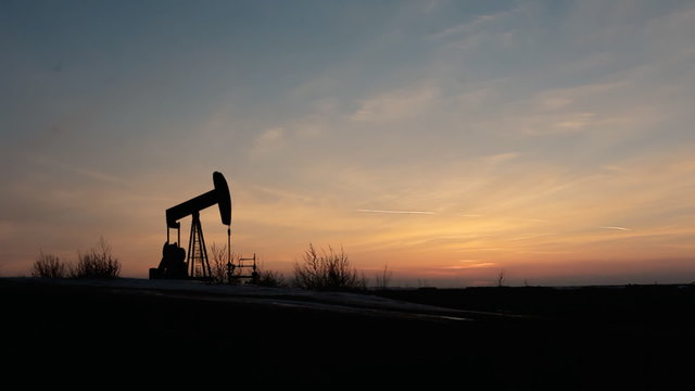 working oil pumps silhouette against sunrise
