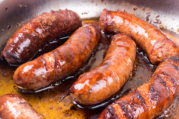 Homemade sausages frying in fat