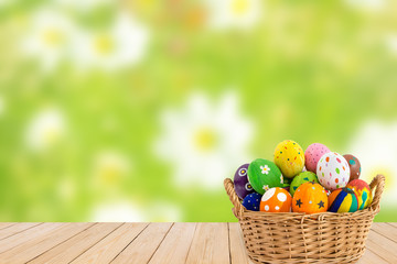 Fototapeta na wymiar Colorful Easter eggs in a basket on wood texture on green flower