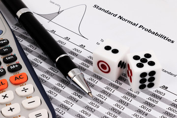 Two dice, calculator and pen on standard normal probabilities ta