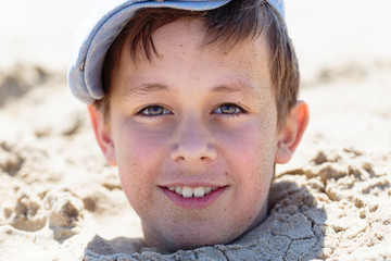 Strandspiele - Junge im Sand eingebuddelt
