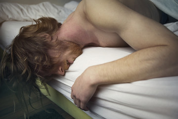 red-haired man lying in bed looking sick