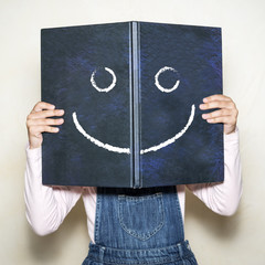 Niña sujetando un libro con cara sonriente