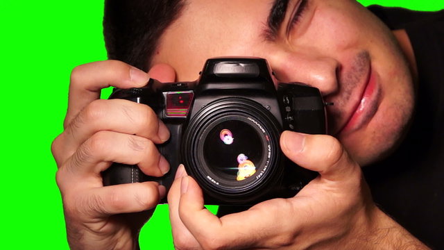 Photographer takes pictures with DSLR camera on a chroma key green screen.