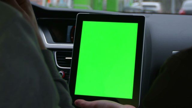 Two People Riding In The Modern Car And Discuss The Route In Tablet With Green Screen