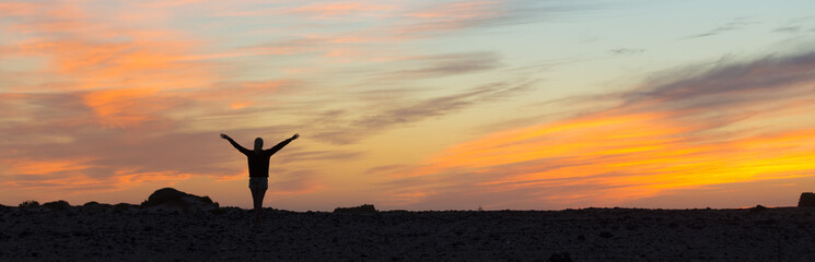 Silhouette of free woman enjoying freedom feeling happy at sunset. Serene relaxing woman in pure...