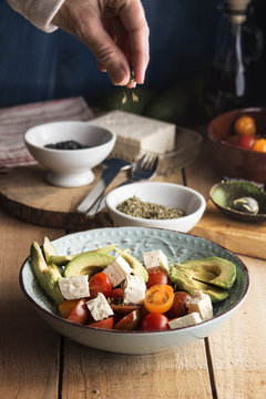 Dressing cherries tomato salad with feta cheese, avocados and oi