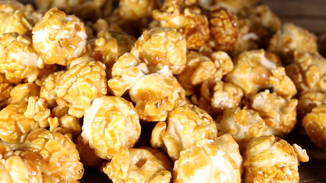 Sweet caramel popcorn on wooden background. Macro shot.