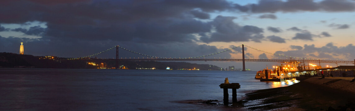 Night time panorama of the river Tagus the Ponte 25 de Abril and the Monument of Cristo Rei Lisbon Portugal