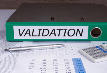 Validation binder in the office with pen and calculator on statistics report