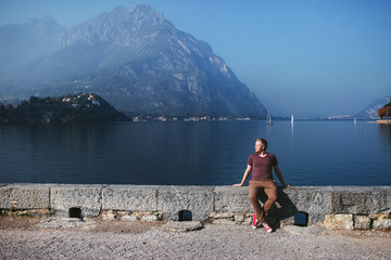 man sits on the waterfront of a mountain lake Como