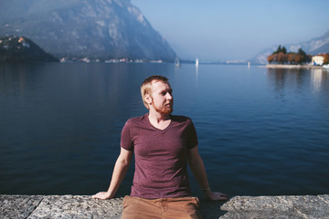 Fototapeta na wymiar bearded man on the background of a mountain lake Como