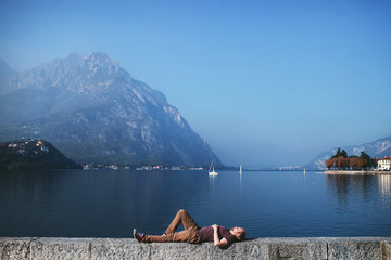 man lying on the embankment of a mountain lake Como