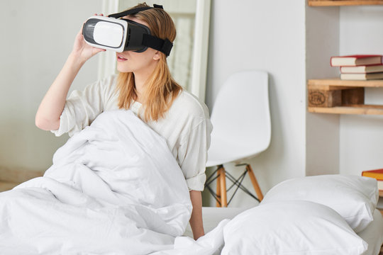 The girl in the virtual reality helmet on the bed