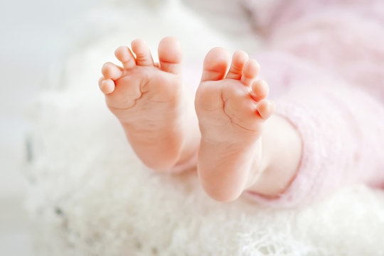 Close up picture of newborn baby feet on knitted plaid 
