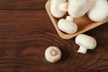 Fresh raw porcini boletus mushrooms in square bamboo bowl. Wood background.