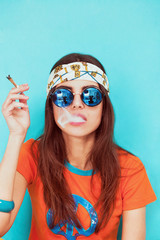 Boho girl portrait wearing blue sunglasses and smoking weed - 105738336