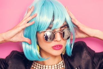 Fashionable and odd girl portrait wearing blue wig and sunglasses